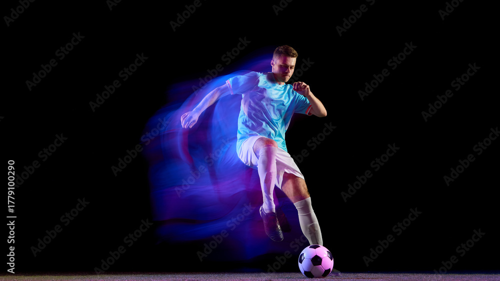 Fototapeta premium Soccer player leaping for powerful header with neon light motion. Concept of passion, precision, and strength used in sports campaigns, teamwork visuals, and modern athletic branding.