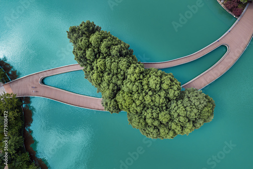 Aerial view of a jade-colored lake embracing a verdant island, bisected by a gracefully curving bridge, Panglong Waterfall Park, Kunming, China.