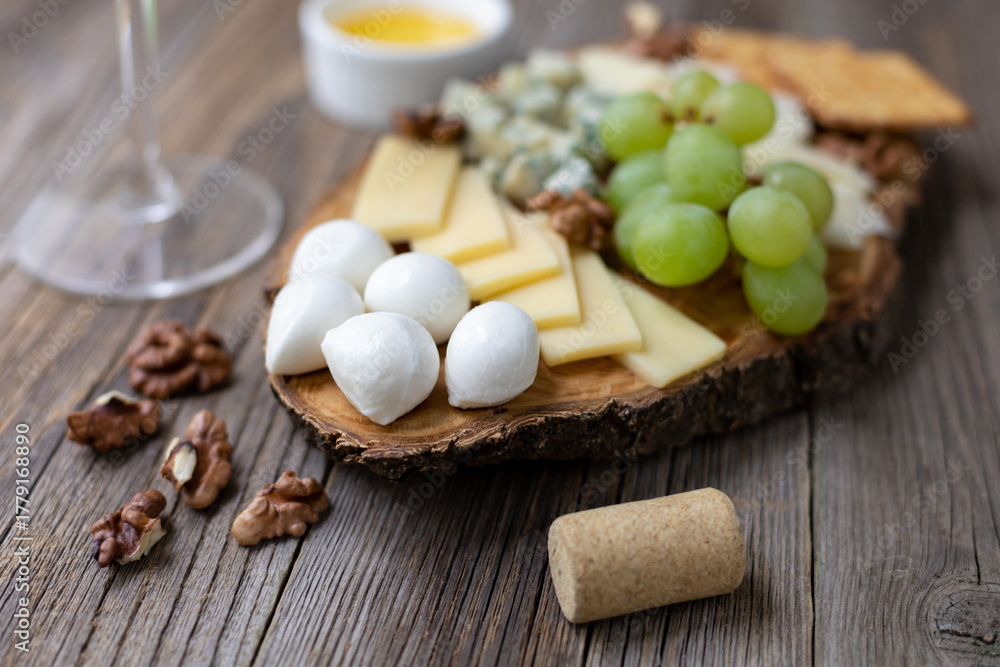 Fototapeta premium Elegant wine and cheese board with grapes and nuts on rustic wooden table