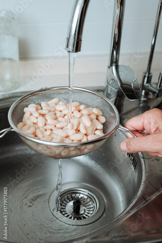 Фотография rinsing white beans in the kitchen sink