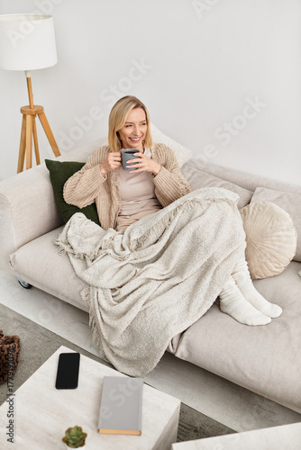 Quadro su tela Blonde woman enjoying cozy moments at home with a warm drink on a winter day