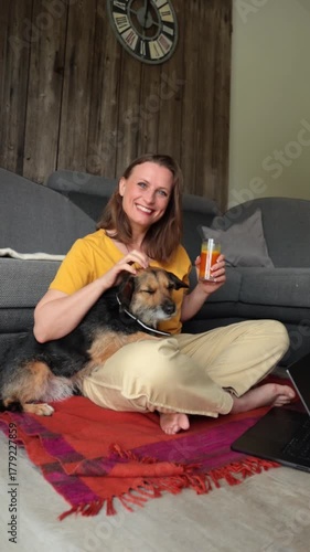 Woman relaxing at home with her dog and a glass of fresh juice. Concept of remote work, healthy lifestyle, pet companionship, and cozy home atmosphere