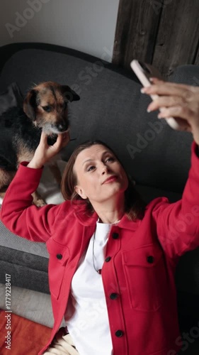 Woman working remotely with laptop, taking a selfie with her dog at home. Happy freelancer enjoying break with pet, sitting on floor in cozy living space, casual digital lifestyle