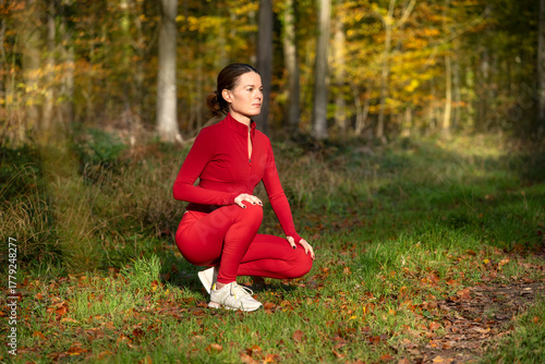 fit sporty woman kneeling resting before exercise and running in the park