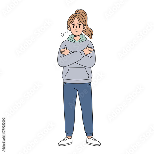 Anxious young woman with arms crossed wearing a gray hoodie and blue pants standing against a black background feeling uncertain and worried with her expression conveying concern and discomfort