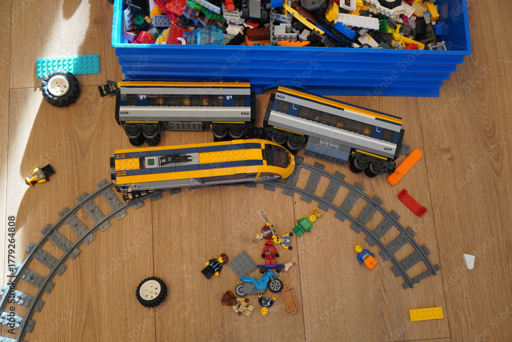 Naklejka premium Toy train set with tracks and colorful toy figures on a wooden floor