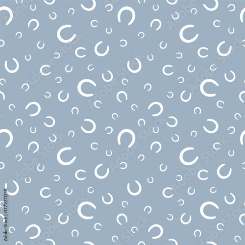 Seamless pattern of white horseshoes in various sizes on soft blue background