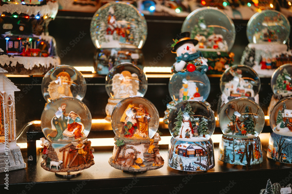 Fototapeta premium Collection of Christmas snow globes featuring nativities, snowmen, and winter scenes on display