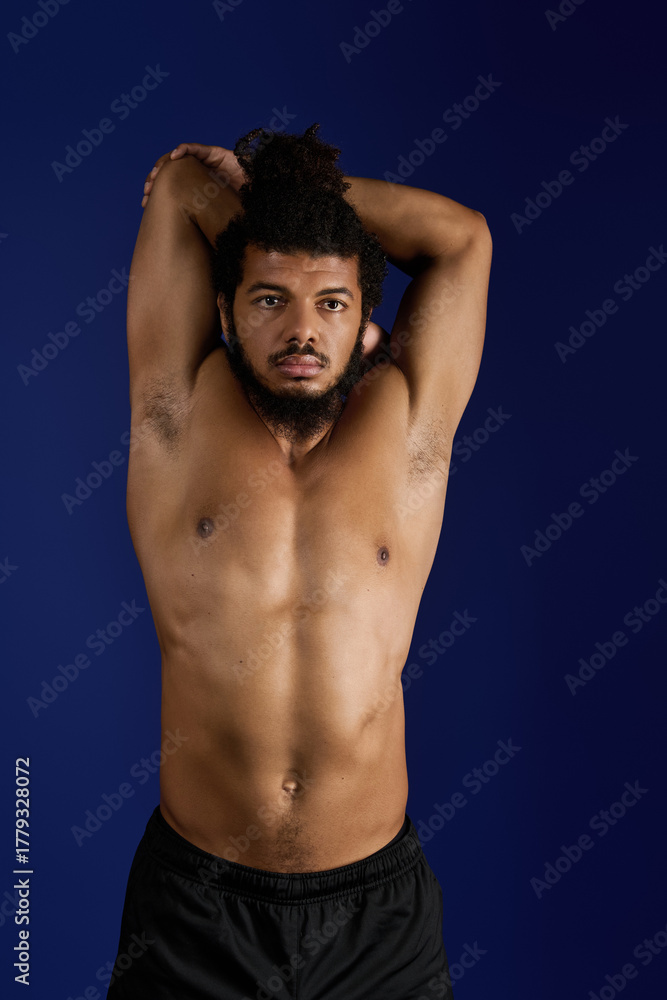 Naklejka premium Sportive man stretching in workout routine against a vibrant blue backdrop