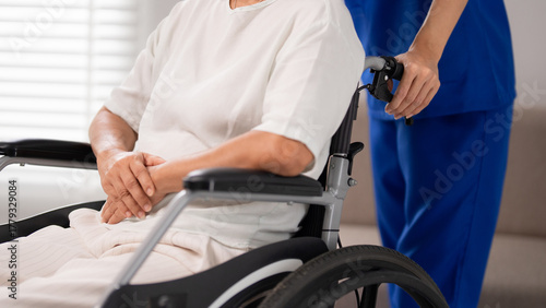 Billede på lærred Nurse caregiver assisting older adult patient in wheelchair providing essential
