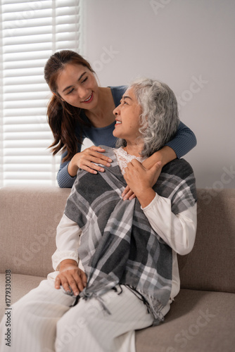 Asian young woman embraces loving elderly grandmother demonstrating gentle home care family bond support and affection