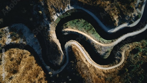 Fototapeta Naklejka Na Ścianę i Meble -  Aerial view of a winding mountain road with tight switchbacks cutting through rugged terrain. Concept Aerial landscape photography, Winding mountain road switchbacks, Rugged mountainous terrain