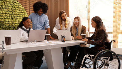 Inclusive diverse business team meeting with woman using wheelchair at modern office