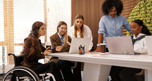 Inclusive diverse business team meeting with woman using wheelchair at modern office