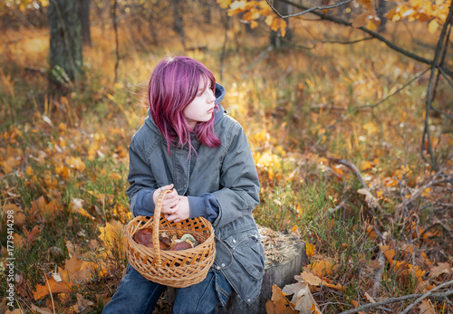 Young girl holding mushroom basket in autumn forest