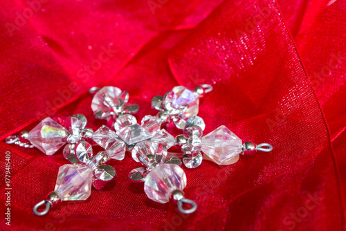A Christmas tree decoration, made from crystal beads to look like a snowflake on a red material