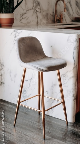 Modern gray velvet bar stool with copper legs in marble kitchen interior