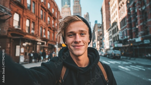 a casual selfie of a handsome 20 years old blond man influencer. Background is new york city streets and buildings. His face is smiling
