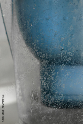 Close-up of limescale buildup on a water filter surface, showing mineral deposits and hard water residue in household appliance.