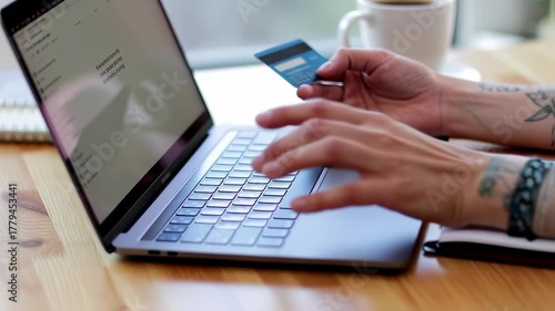 Person holding credit card and typing on laptop, near a coffee mug, on wooden surface
