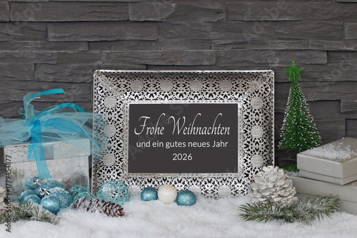 Winterliche Kulisse mit Geschenken und Weihnachtsschmuck im Schnee auf einem Rahmen steht der Text frohe Weihnachten und ein gutes neues Jahr.
