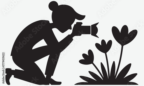Silhouette of a photographer kneeling to capture images of blooming flowers