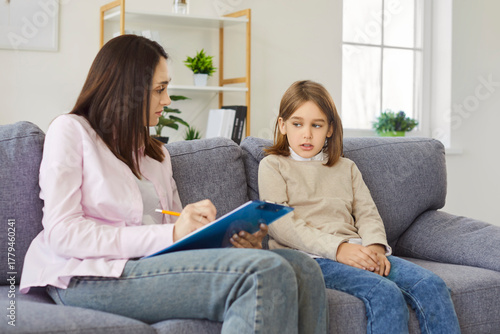 Pensive child talking to psychologist about thoughts and feelings. Boy meeting with therapist for behavior problem counseling, psychology therapy office, counselor writing notes during session