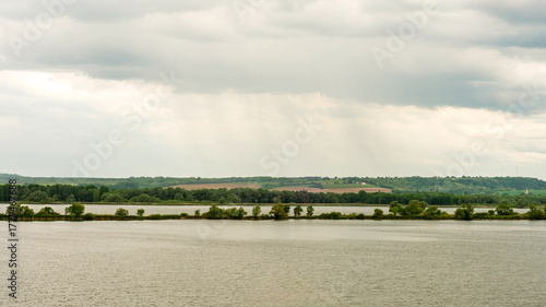 Calm Lake and Farmland under Cloudy Sky