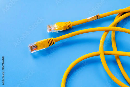 Yellow RJ45 Ethernet cable on color background.