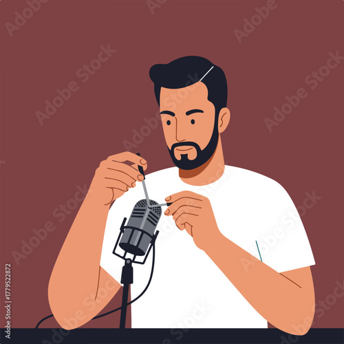 A bearded man in a white t-shirt adjusts a microphone, seemingly preparing for a recording