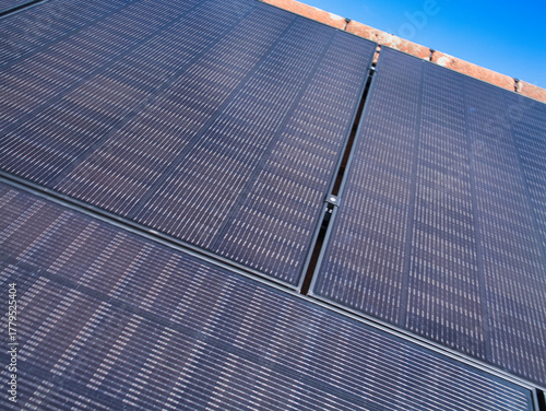 Close-up of photovoltaic panels on a house roof against a bright blue sky in the United Kingdom, symbolizing clean power and modern home efficiency.