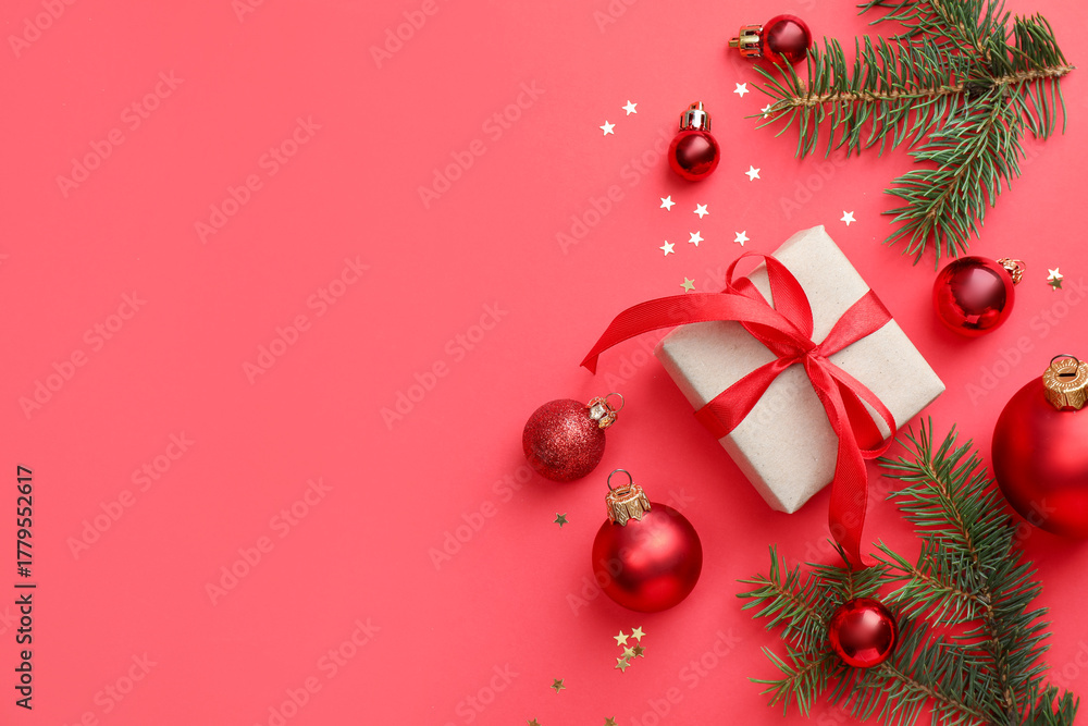 Obraz premium Fir tree branches, gift and Christmas decor on red background, flat lay. Space for text