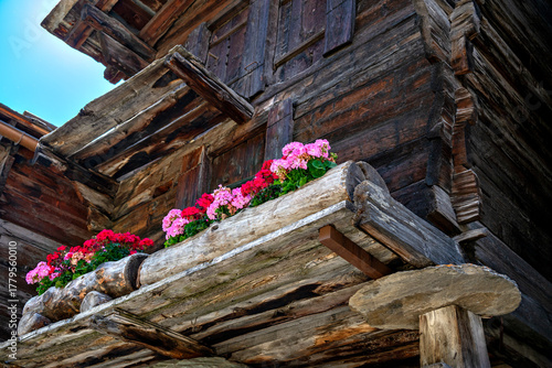 Old barn for storing provisions with stone discs to protect against mice, decorated with flowers, in Zermatt in the canton of Valais, Switzerland