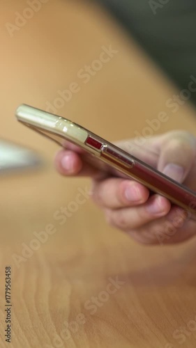 Closeup two young students are reading a text on phone. Children looking smart phone screen over a wood desk in classroom. Teenager hand holding smartphone search information. Education concept
