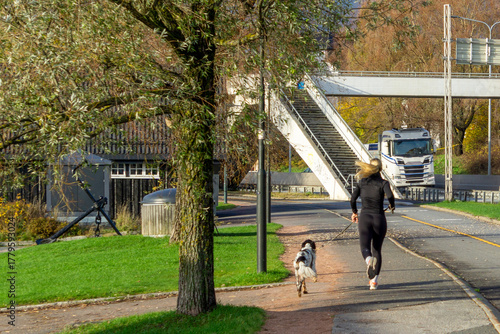 Rear View of Woman Jogging with Dog Outdoors, Active Lifestyle and Pet Exercise Concept in Urban Environment