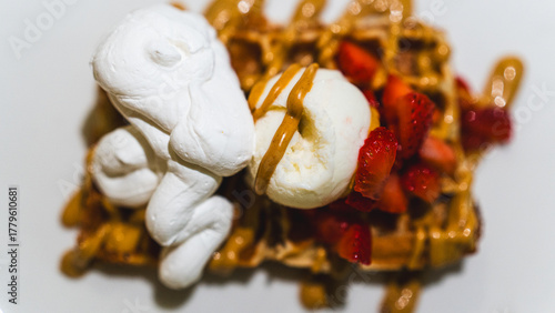 Fotografia Crispy waffle topped with vanilla ice cream, chocolate sauce, caramel, and fresh fruits