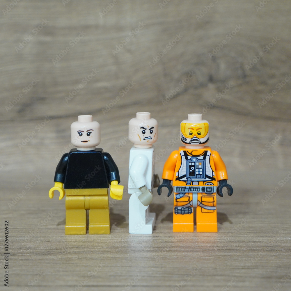 Naklejka premium Three Lego Minifigures Standing Together on a Wooden Surface