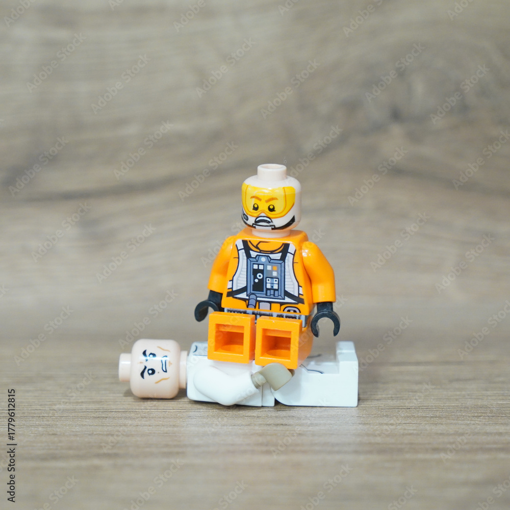 Fototapeta premium Lego minifigure in orange pilot suit sitting on another Lego figure