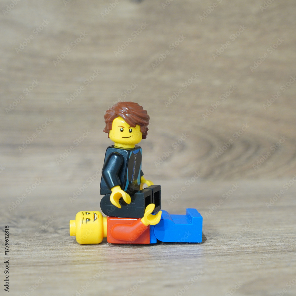 Naklejka premium Lego minifigure sitting on another, concept of power and dominance