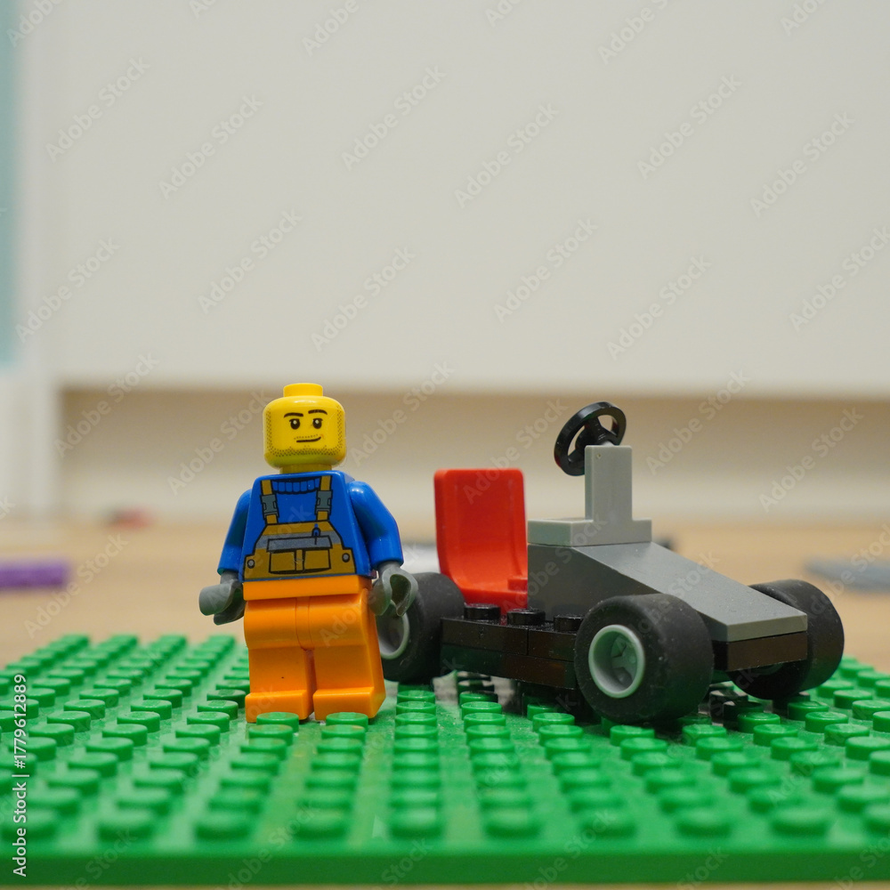 Naklejka premium Lego minifigure with a small race car on a green baseplate