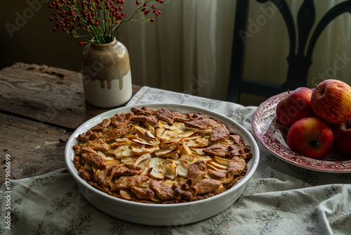 Homemade apple pie decorated with crust on wooden table in rustic kitchen.
