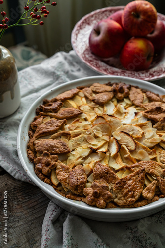 Homemade apple pie decorated with crust on wooden table in rustic kitchen.