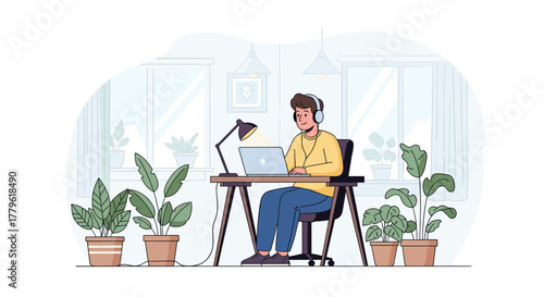 Focused young man working remotely on laptop wearing headphones in a bright, plant-filled home office space