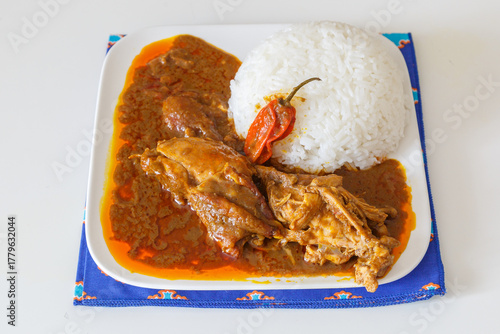 Sauce graine, spécialité ivoirienne à base de pulpe de palmier à huile, servie avec du riz dans une assiette blanche. Spécialité africaine. 