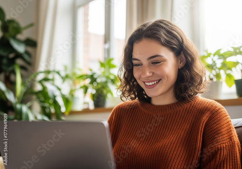 Young woman with curly brown hair smiling at laptop screen curly hair happy