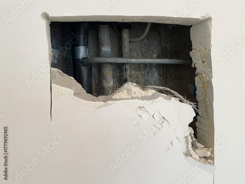 Hole in the wall, close-up. Pipework repair. Problem during renovation or construction. No access panel to see riser. To access pipes and fix emergency leak, wall had to be broken down