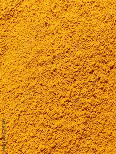 Turmeric powder creating colorful food spice background texture