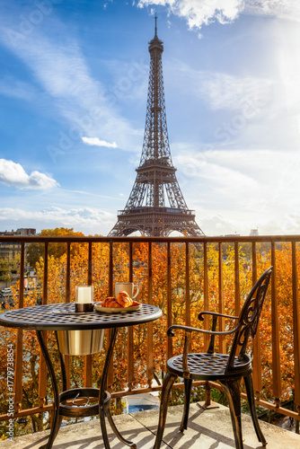 Photography A balcony with a breakfast table and empty chair with view of the Eiffel Tower i
