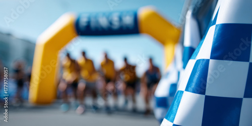Wallpaper Mural Blurred runners at the starting line of a race with a yellow inflatable arch and checkered flags in the foreground under clear blue sky Torontodigital.ca