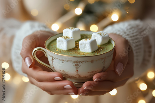 Warm winter hands with cup. Cozy pistachio mug with marshmallows. Holiday comfort aesthetic.